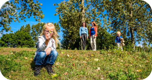 Kind in het gras met mensen op de achtergrond